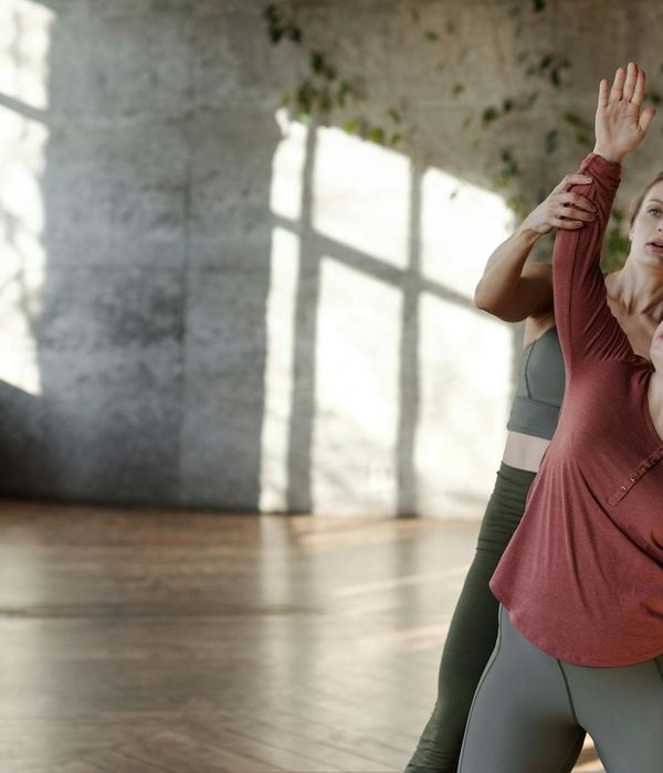 Person stretching gently on a yoga mat in a sunlit studio.